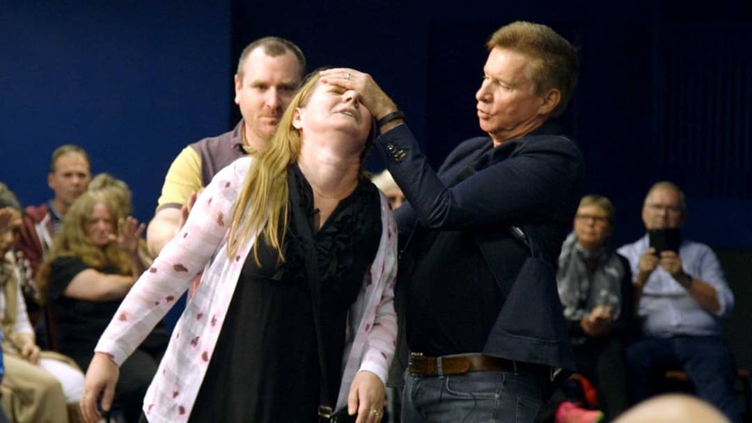 A public faith-healing service where a minister prays for a participant.